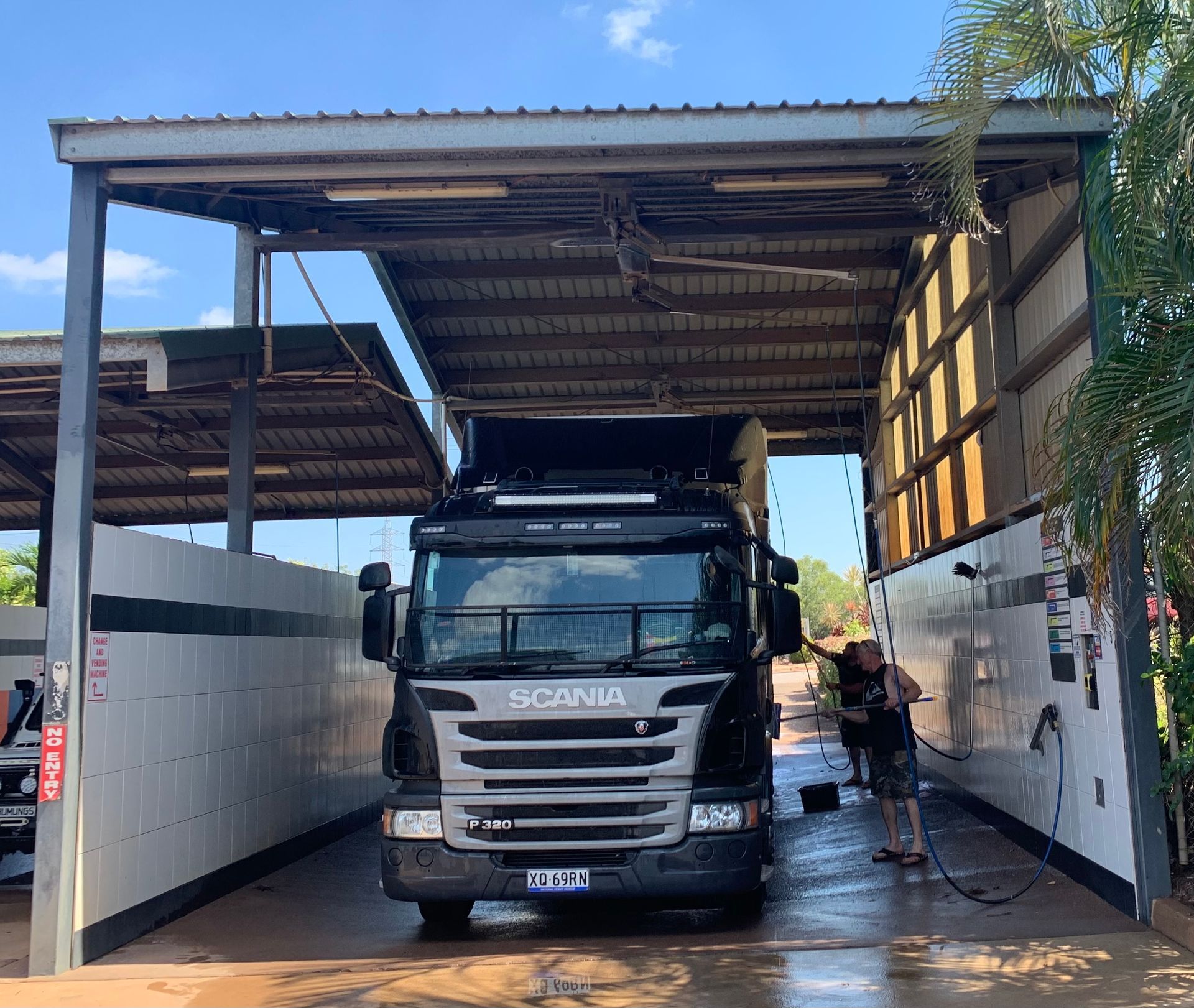 Truck stuck under low roof at a vehicle wash, with a person standing beside it — Ezyas Car Wash NT in Yarrawonga, NT