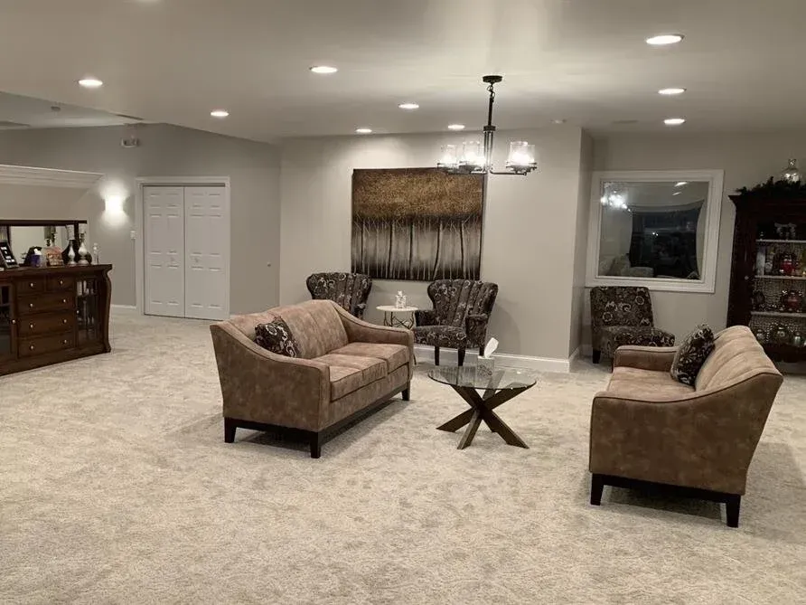 Spacious living room with beige carpet, two sofas, a coffee table, and recessed ceiling lights.