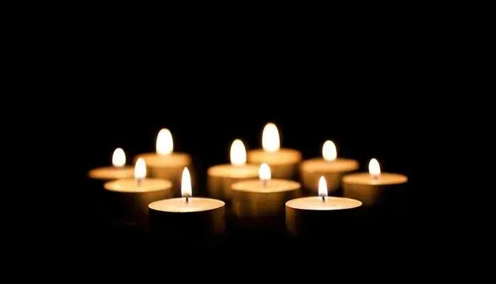 Several lit candles glowing in a dark room