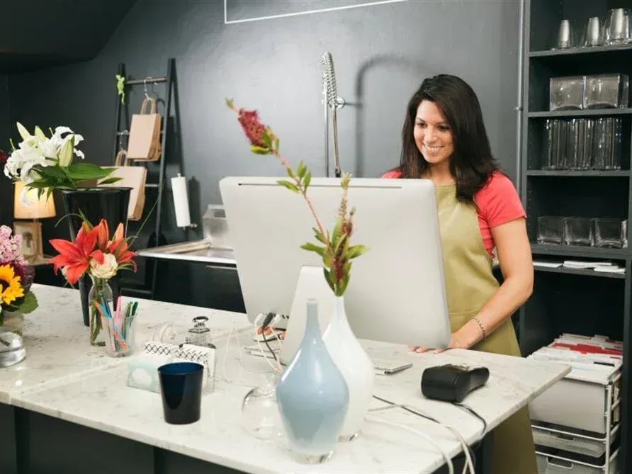 Woman arranging flowers at a counter in a modern shop or studio
