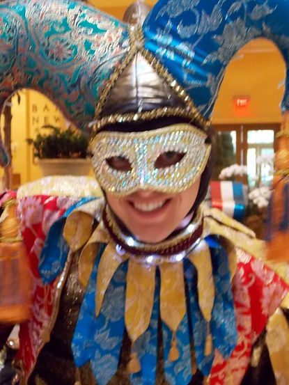 Person wearing a jester costume, smiling, in a brightly lit setting.