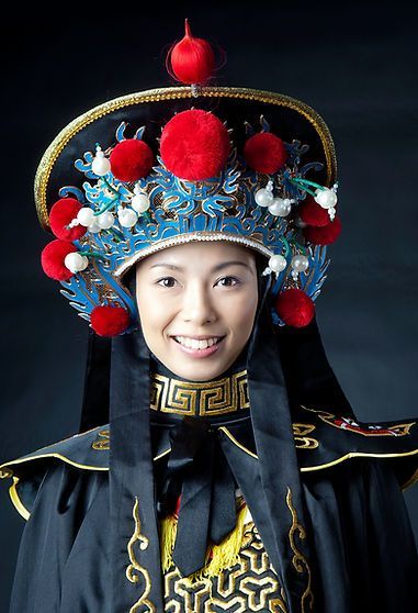 Woman in ornate Qing dynasty headwear and clothing smiling.