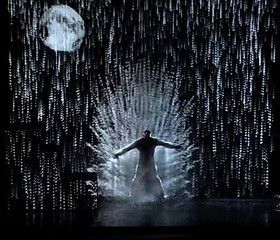 Silhouette of a person with arms outstretched in a dark, icy setting under a full moon.