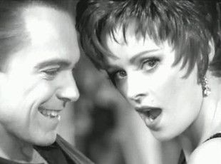 Man smiles at woman, who has a surprised expression. Black and white close-up.