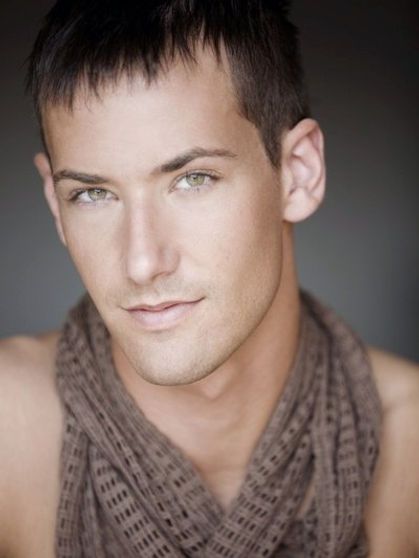 Man with light skin and green eyes, wearing a brown scarf, looking at the viewer.