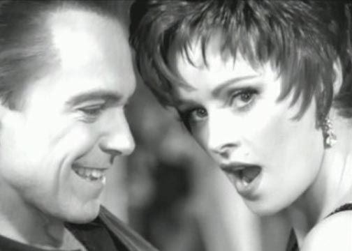 Black and white photo: Man smiles, woman with surprised expression, close-up.