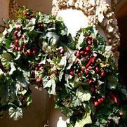 A statue of a green-faced figure, draped in grapevines with red berries.