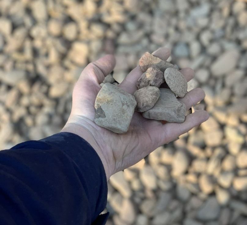A Person Is Holding A Pile Of Rocks In Their Hand — Serious About Landscape Supplies In West Gosford, NSW
