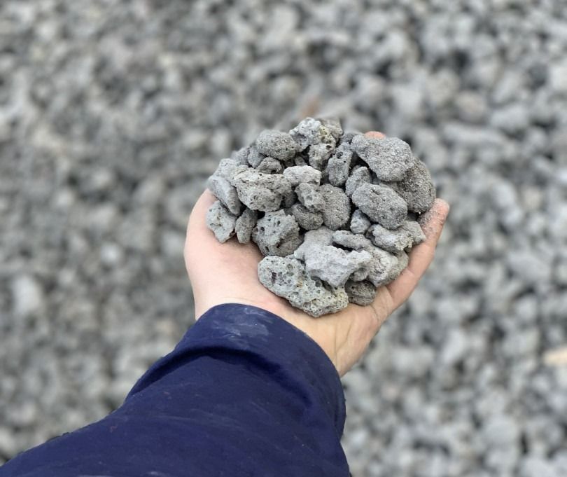 A Person Is Holding A Pile Of Rocks In Their Hand — Serious About Landscape Supplies In West Gosford, NSW