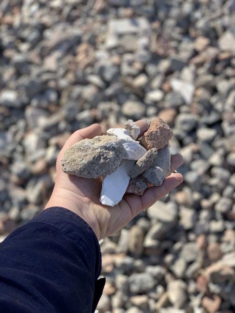 A Person Is Holding A Pile Of Rocks In Their Hand — Serious About Landscape Supplies In West Gosford, NSW