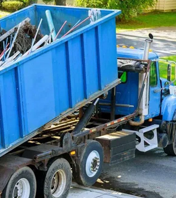 Blue dump truck loaded with a dumpster and scrap metal