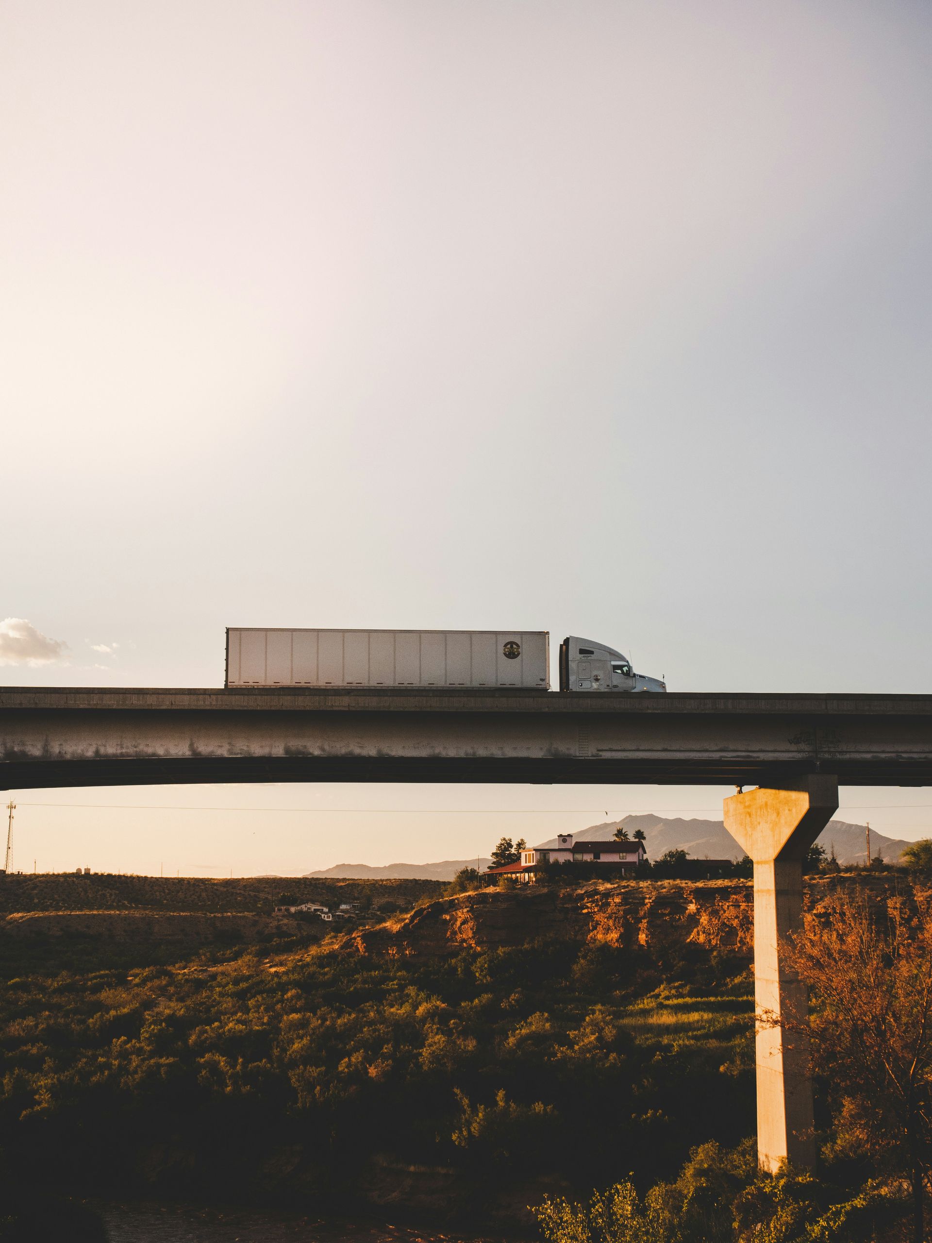 A truck is driving on a highway over a bridge.