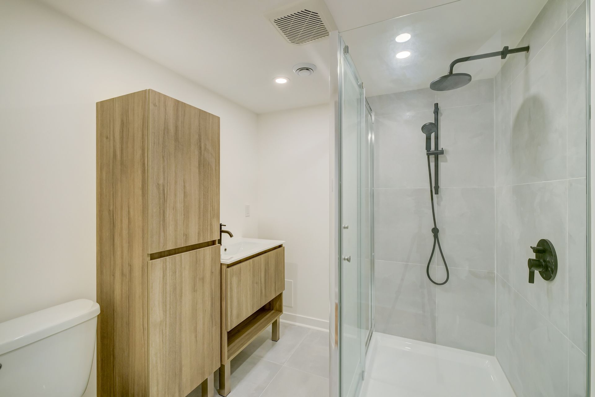 Salle de bains moderne avec meuble-lavabo en bois, murs blancs et cabine de douche en verre