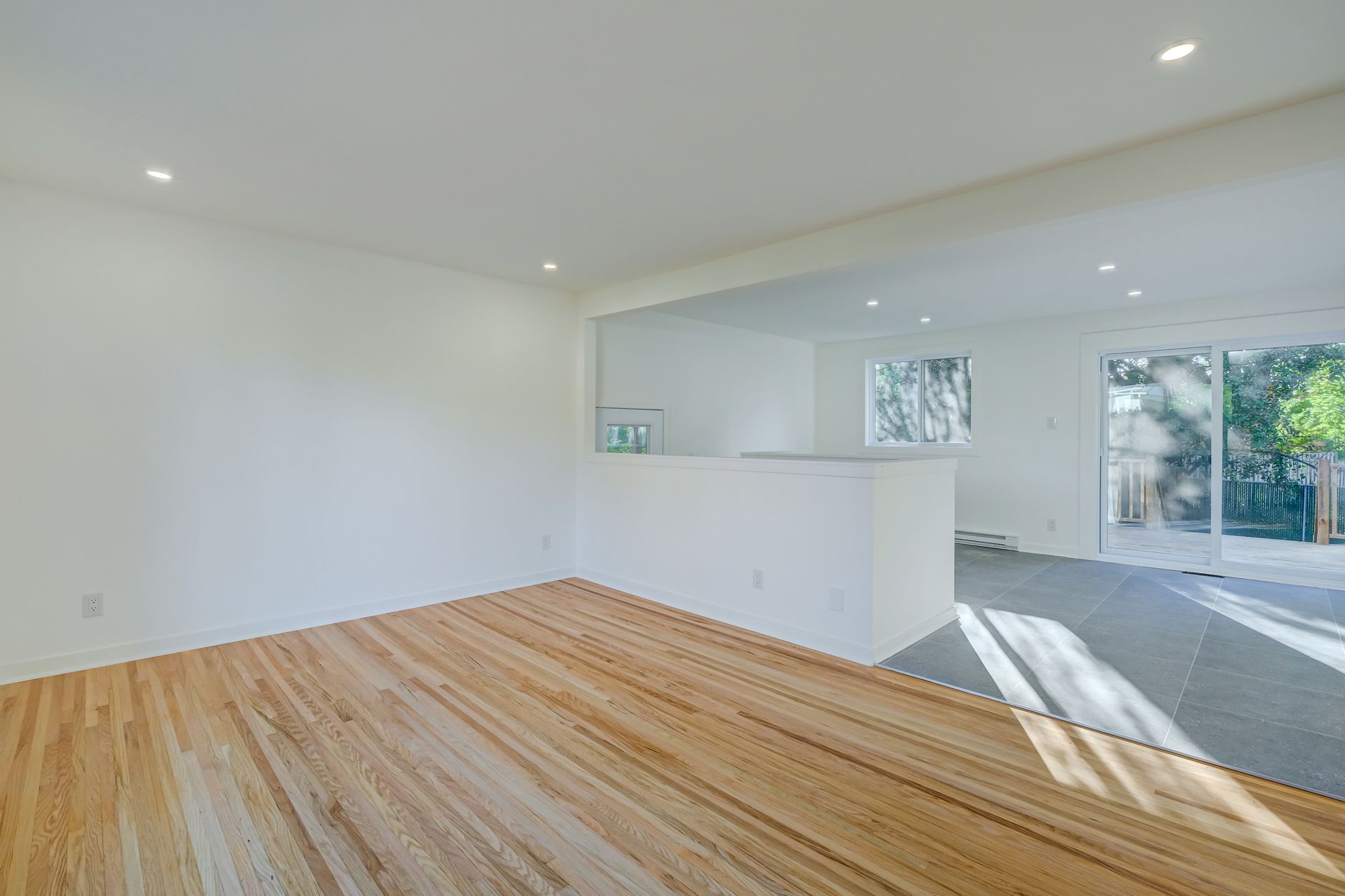 Pièce lumineuse et aérée avec parquet, murs blancs et lumière naturelle grâce à de grandes fenêtres