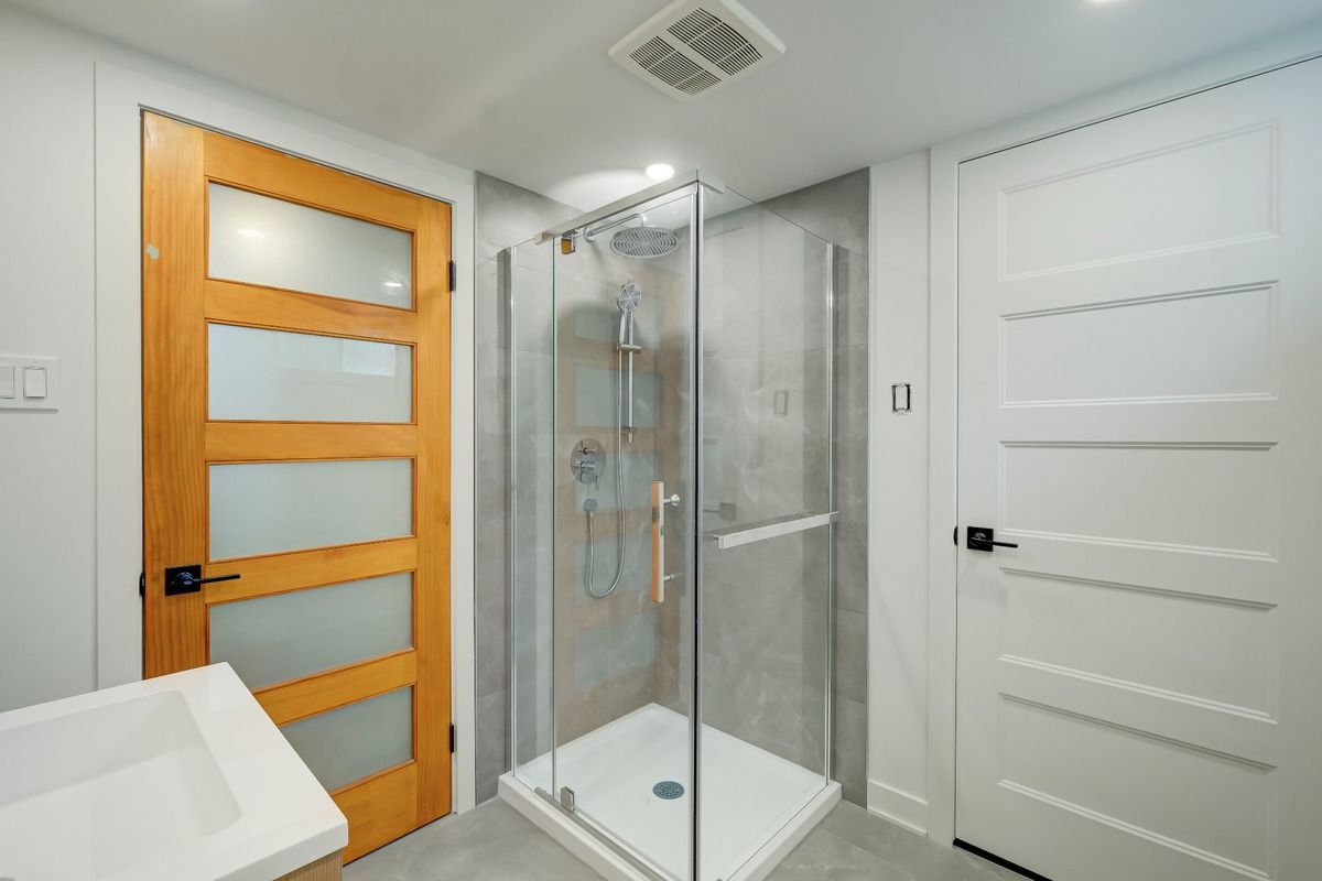 Salle de bains moderne avec douche en verre, porte en bois et porte à panneaux blancs