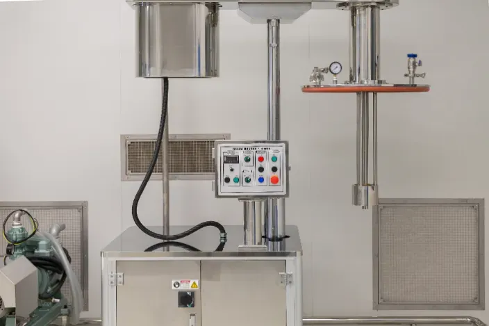 Stainless steel industrial mixing machine in a sterile white room.