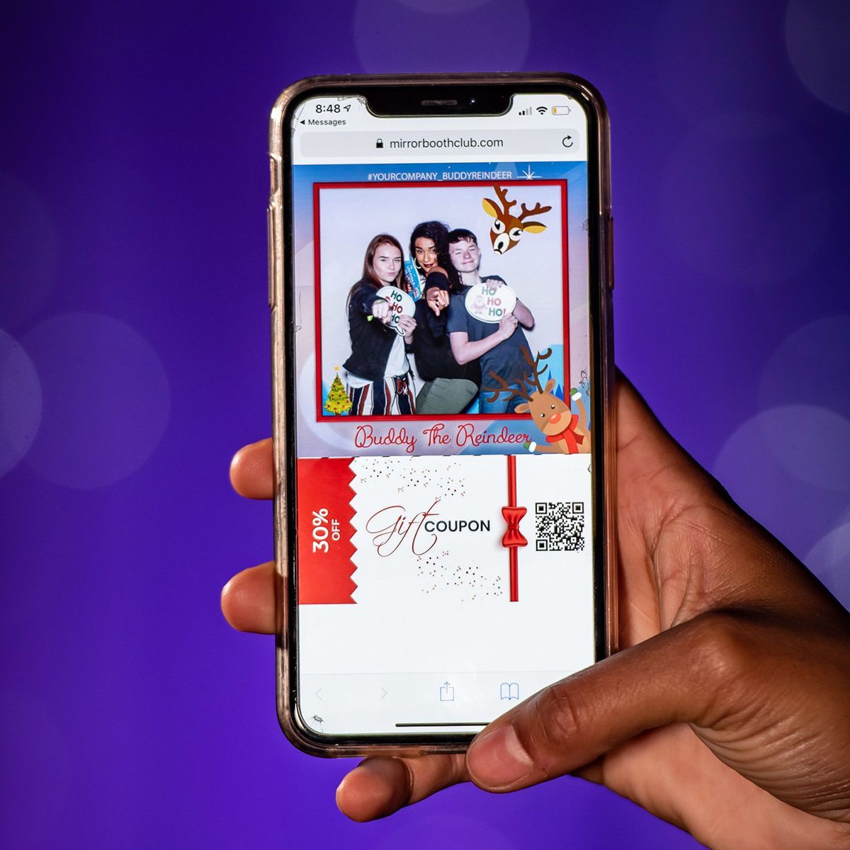 A hand holds a smartphone displaying a digital 30% off holiday coupon featuring a photo of four people with festive props.