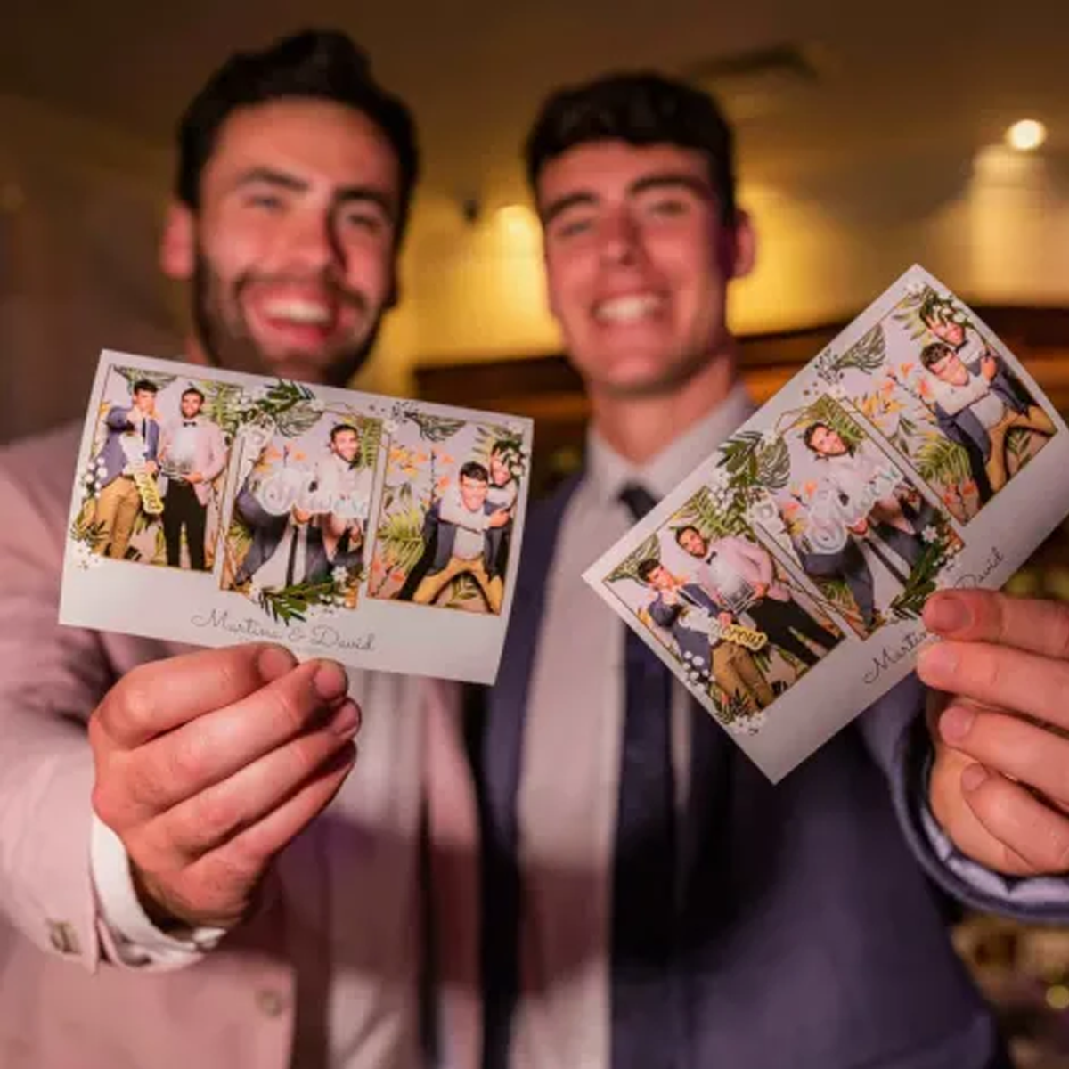 Two smiling people in suits holding up matching photo booth strips featuring three poses each.