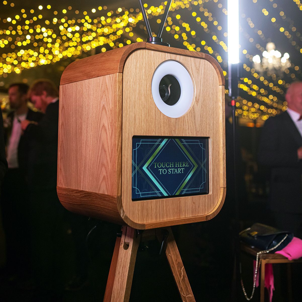 A wooden photo booth with a circular ring light and a screen displaying 
