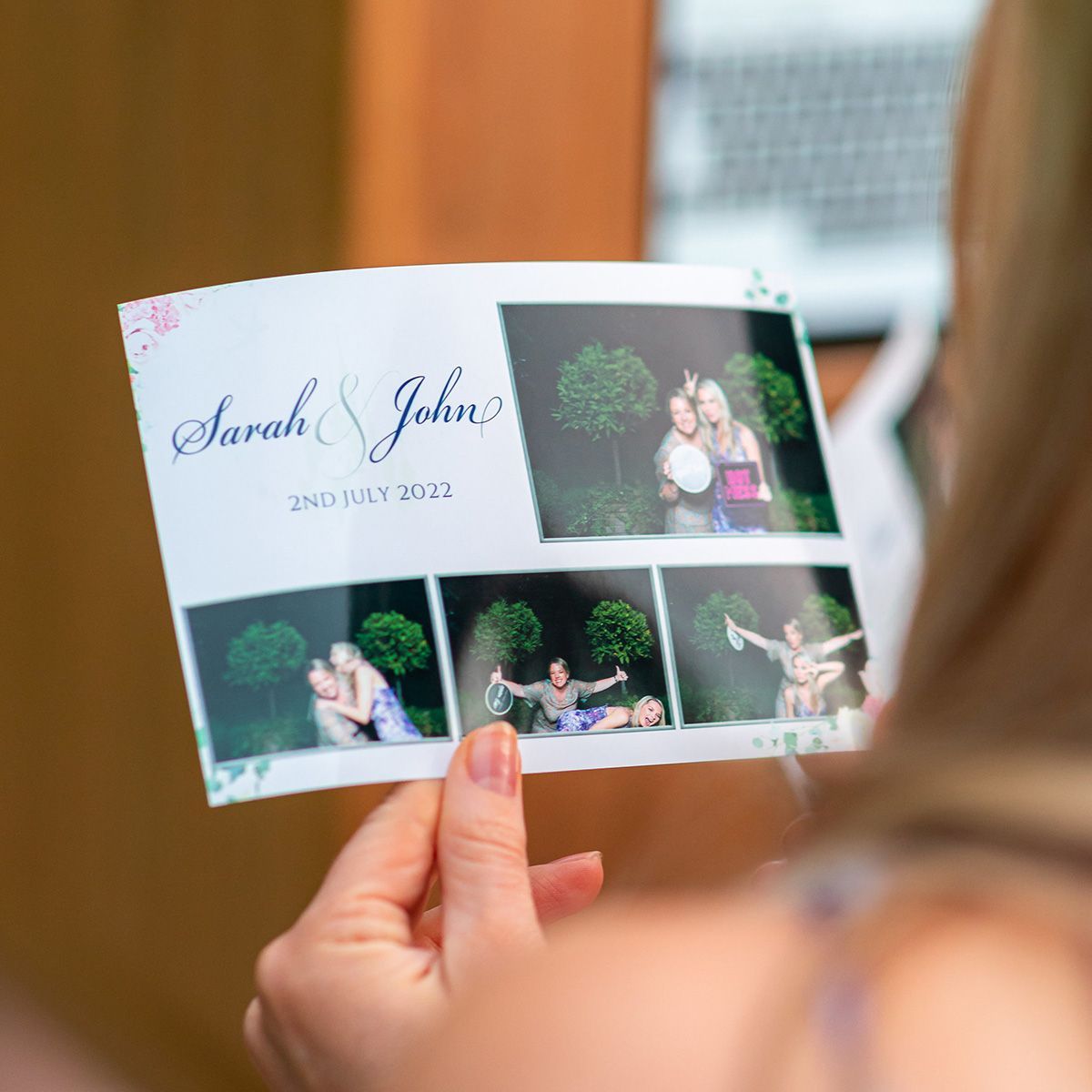 A person holds a wedding photo booth strip titled 