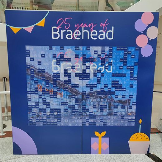 A celebratory Braehead 25th anniversary display wall with a photo collage, bunting, balloons, a gift, and a cupcake.