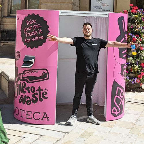 A person stands in front of a pink photo booth that says 