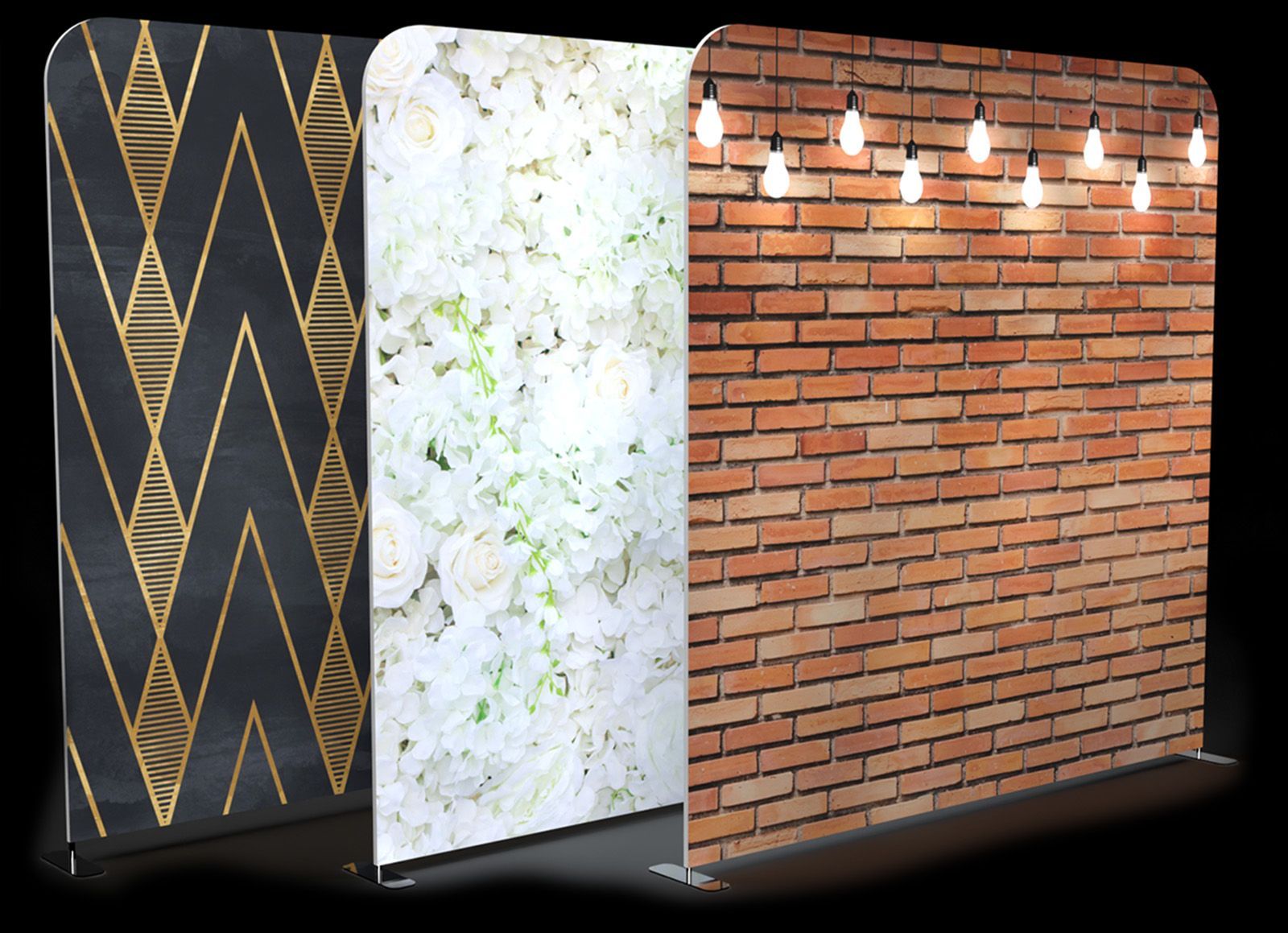 Three standing display banners with different backgrounds: gold-patterned black, white floral, and brick with string lights.