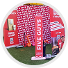 A red Five Guys branded promotional display on a patch of artificial grass, featuring a vertical banner and standees.