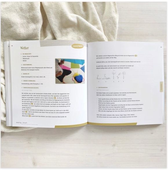 Een open boek op een wit, gestructureerd oppervlak, met brei-instructies en een kleurrijke foto van een handwerkproject met garen.