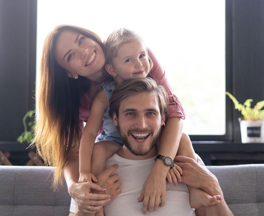 A family is sitting on the floor looking at a laptop computer.