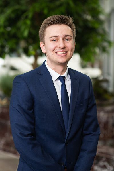 A young man in a suit and tie is smiling for the camera.