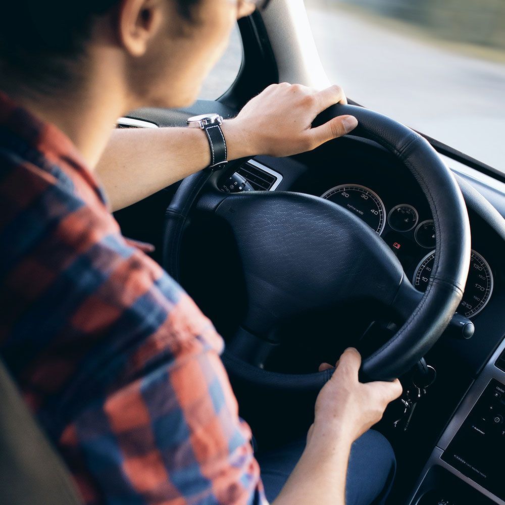 a man in a plaid shirt is driving a car