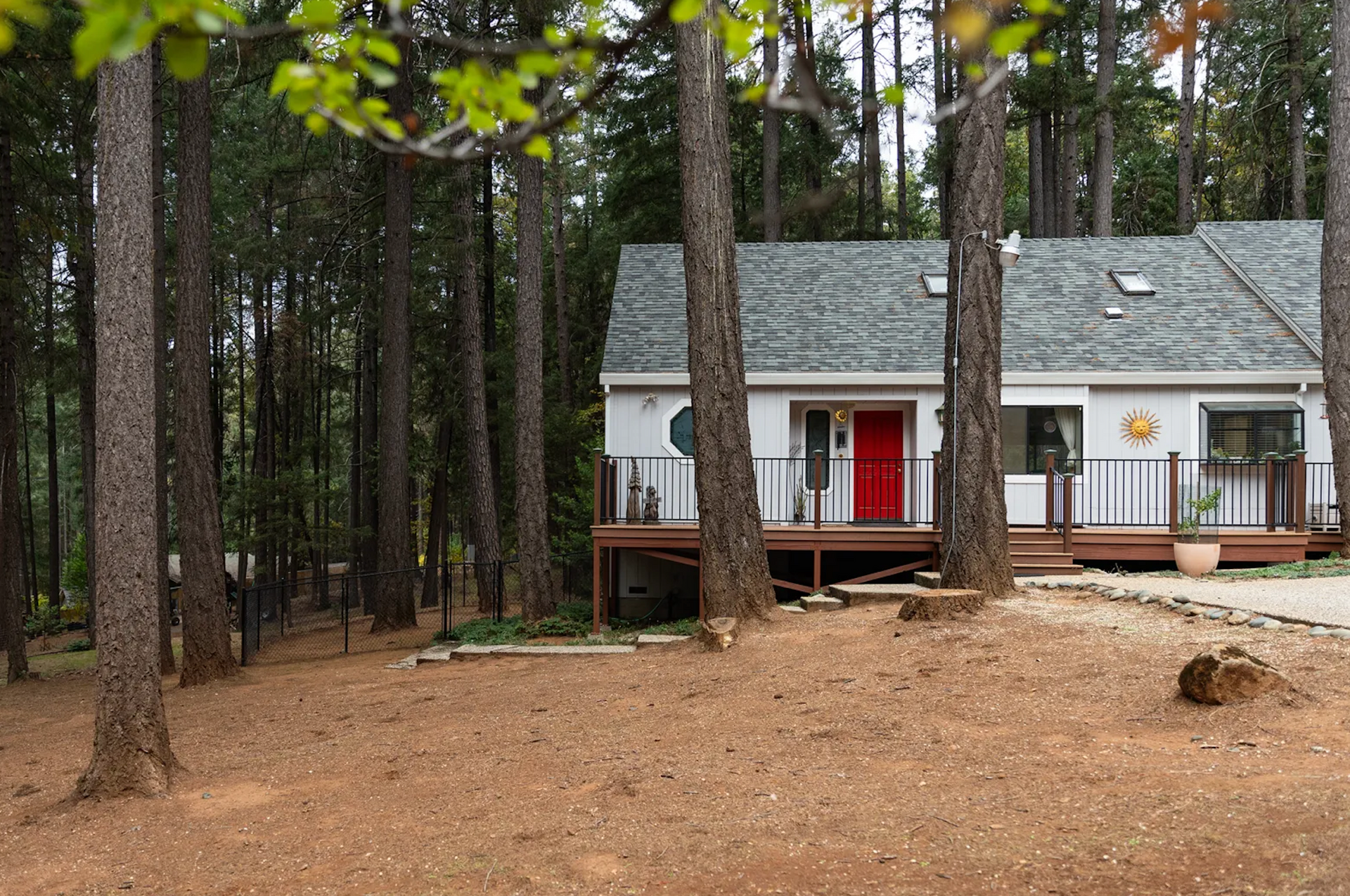 A white house with a red door is surrounded by trees