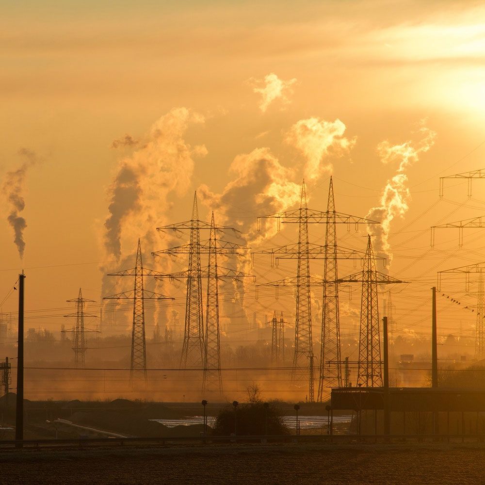 climate There is a lot of smoke coming out of a factory at sunset.