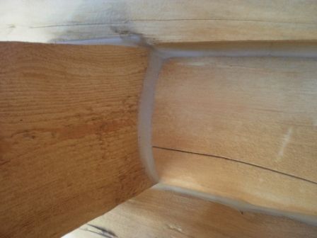 Close-up of wooden corner with a curved, filled seam; light brown tones.
