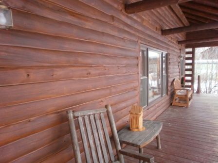 Wooden cabin exterior with porch, rocking chairs, and a small table.