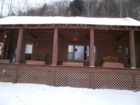 Log cabin with snow on the roof and around the deck.