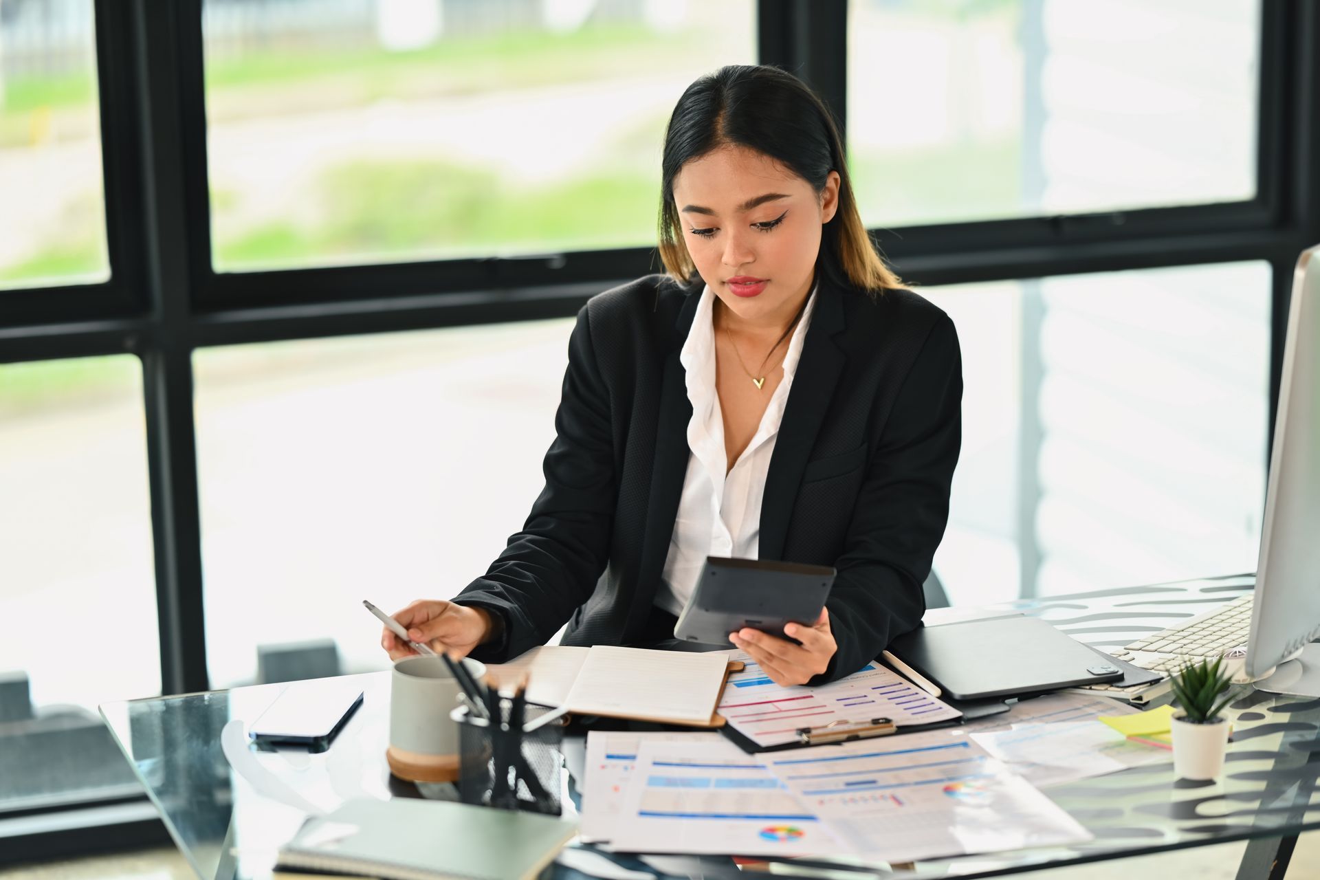 A woman is sitting at a desk in front of a computer.