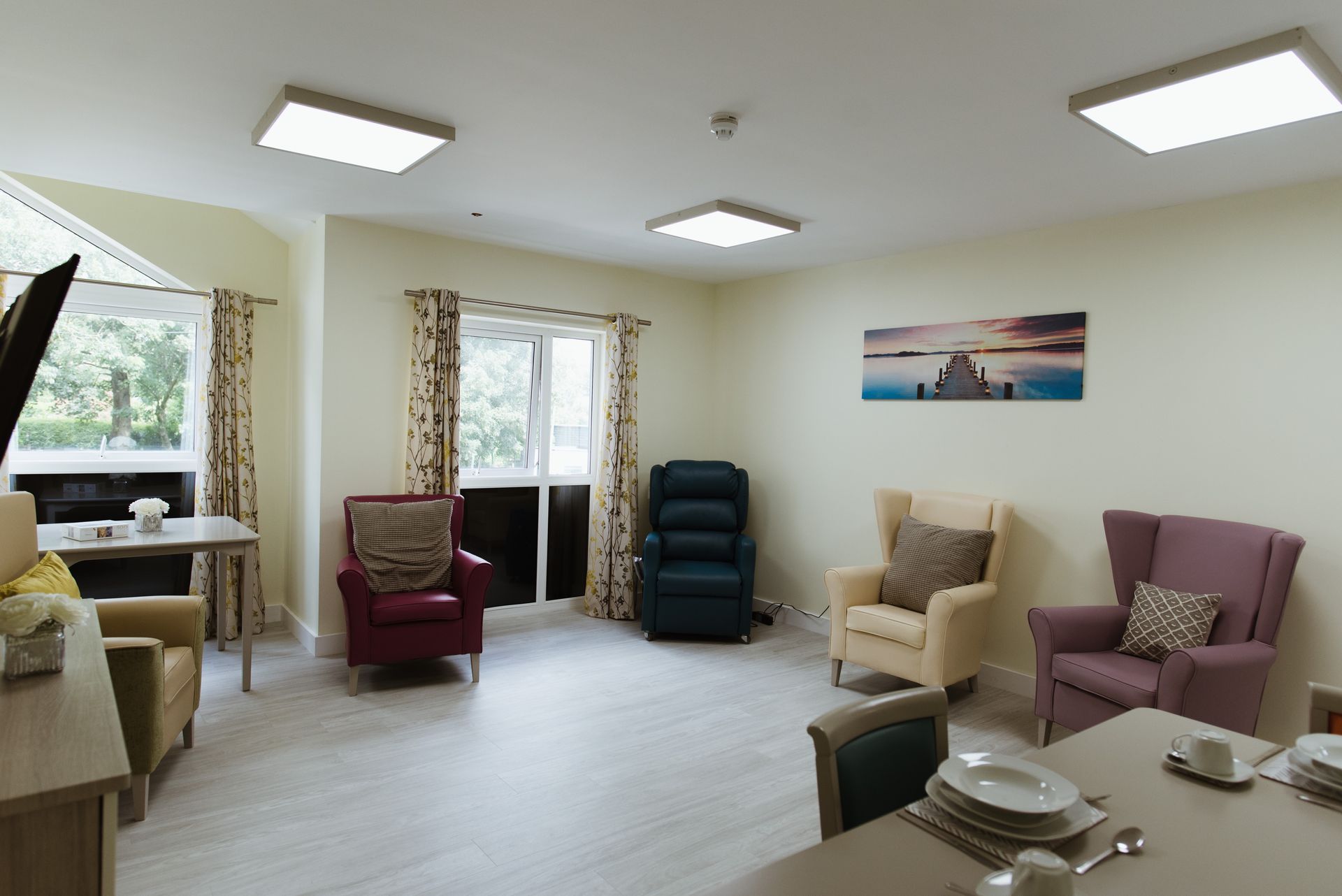 a living room with chairs a table and a painting on the wall