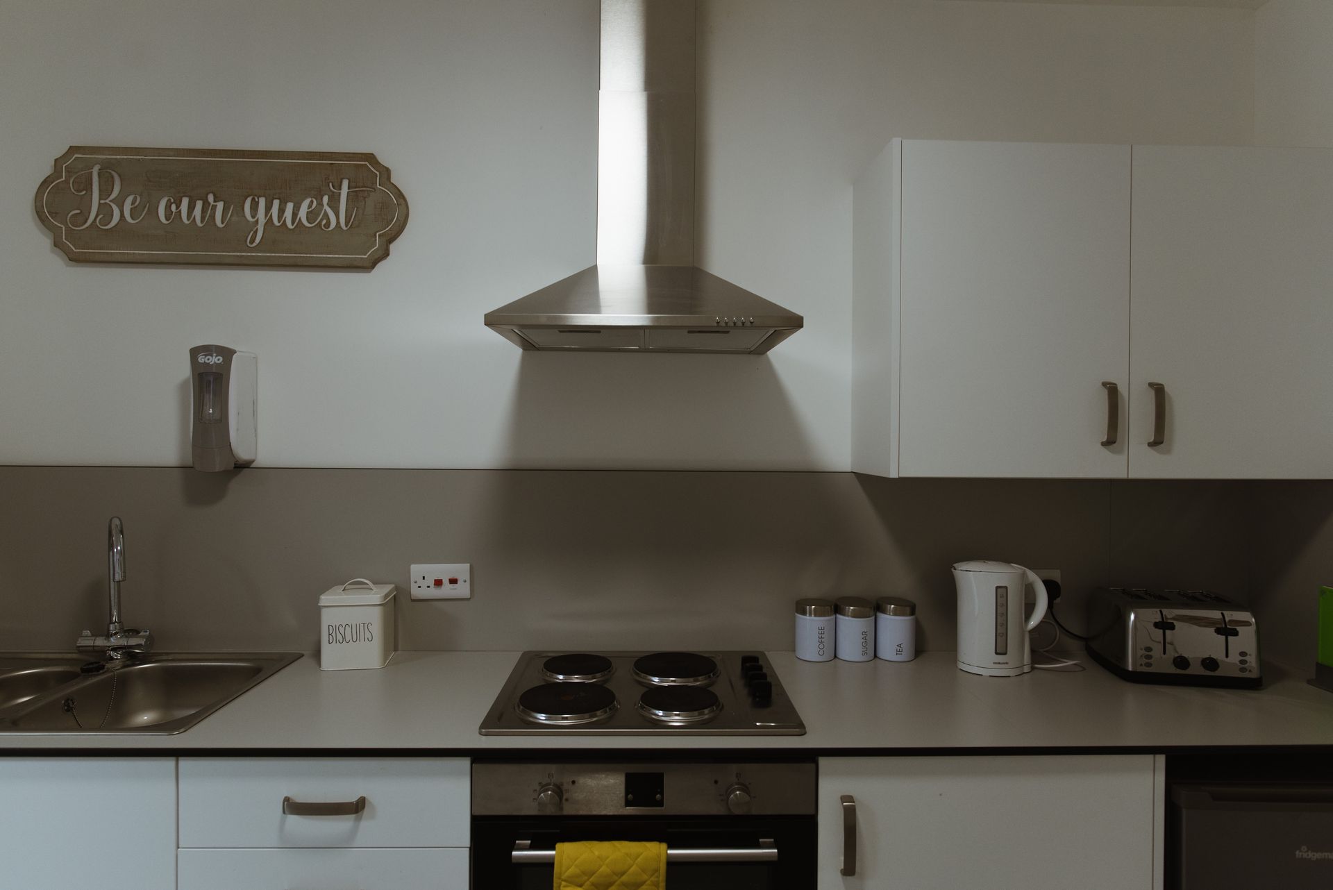 a kitchen with a sign that says be our guest