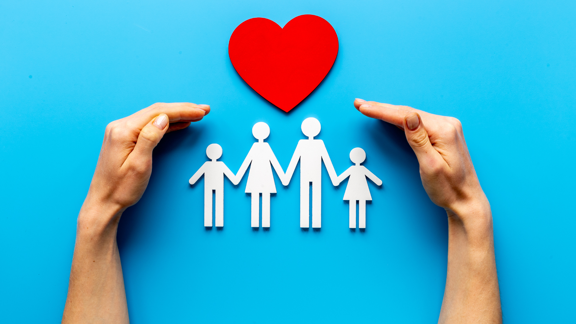 a person is holding a paper cut out of a family and a red heart .