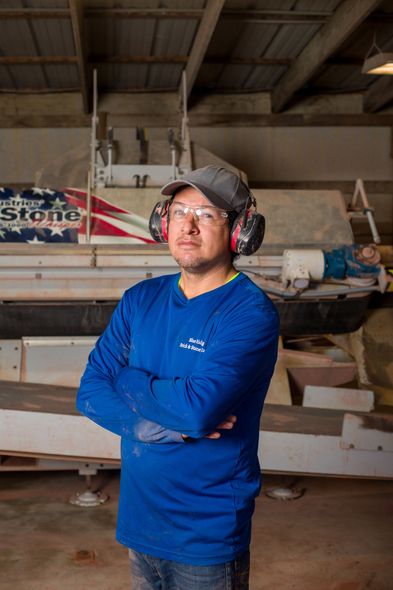 a man wearing ear protectors and a blue shirt stands in front of an american sole sign