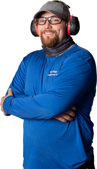 a man wearing a hard hat and blue overalls stands with his arms crossed