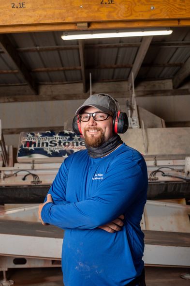 a man wearing headphones stands in front of a sign that says brick and stone cutter