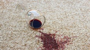 Spilled red wine from a tipped glass on a beige carpet