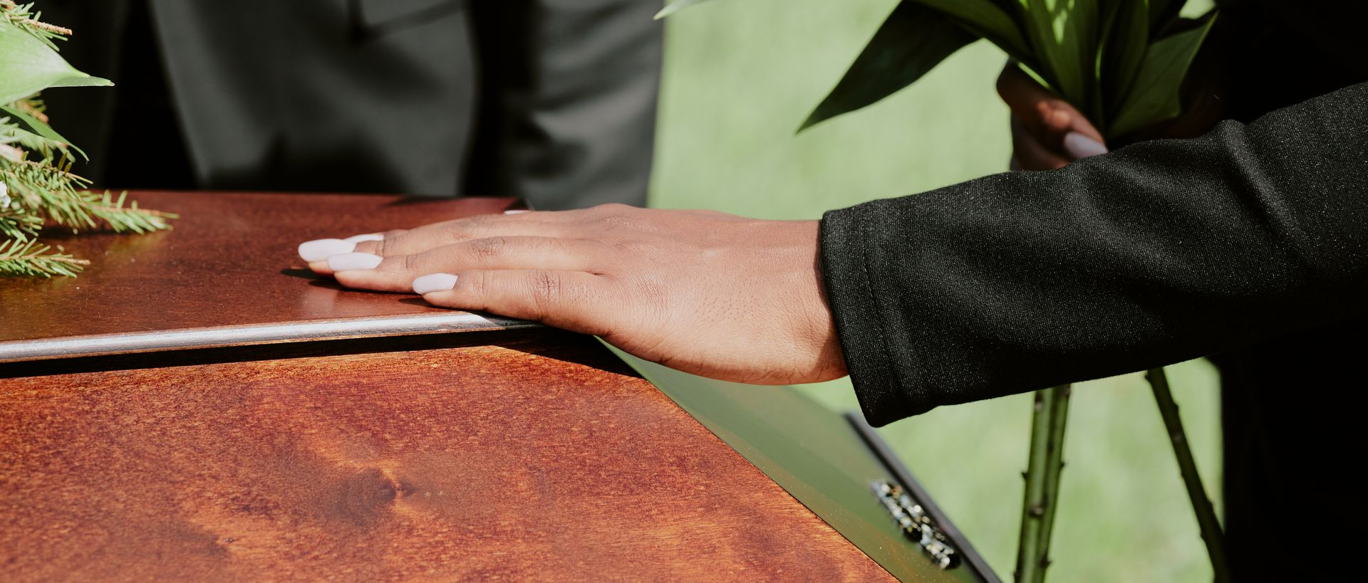 Hand resting on a rusty metal surface beside green plants and a small hand tool
