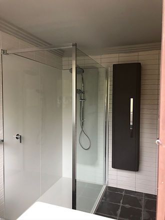 A bathroom with a walk in shower and a black cabinet.