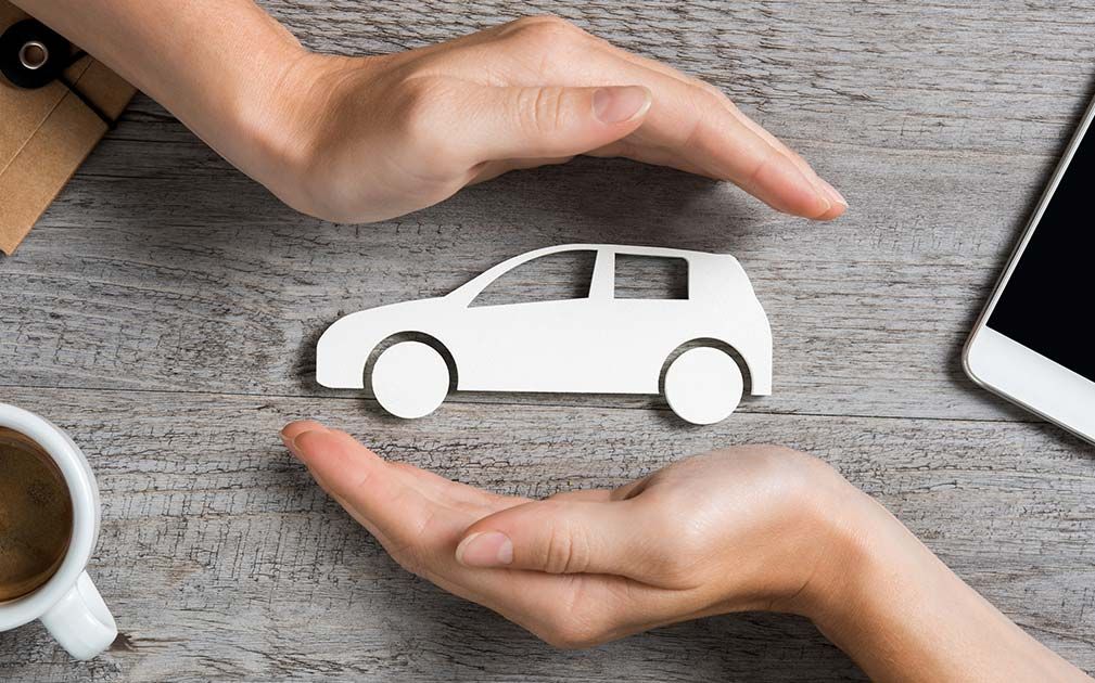 two hands holding a paper car on a wooden table