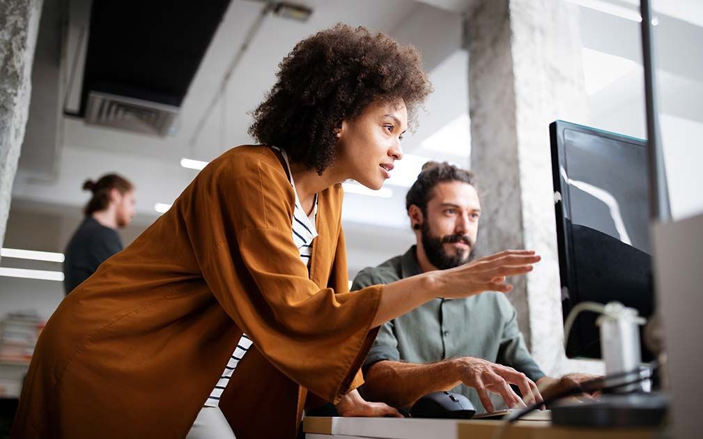 a man and a woman are looking at a computer screen