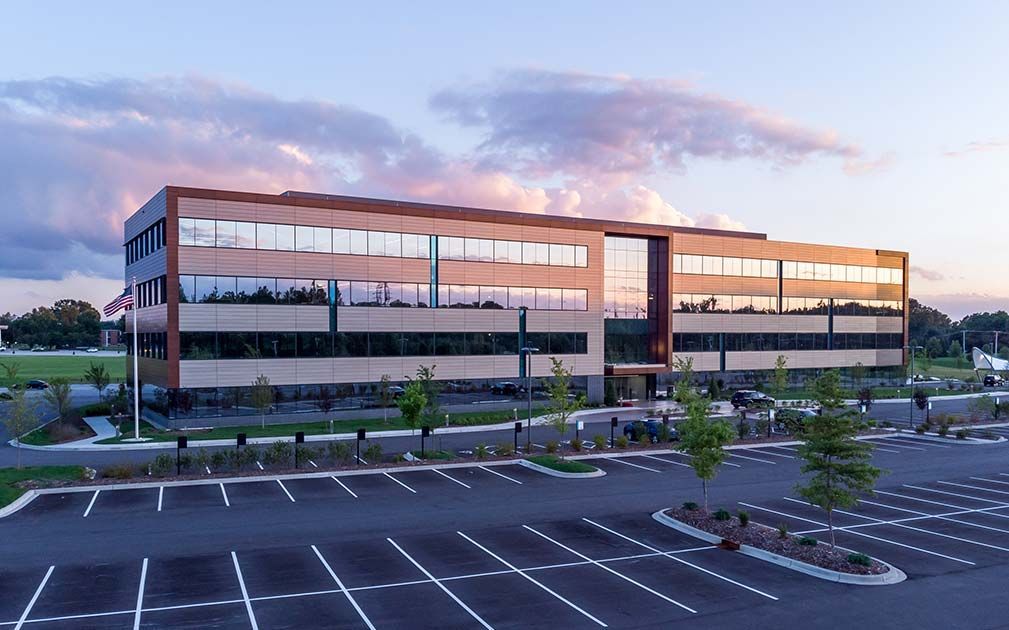 a large building with a lot of windows and a parking lot in front of it